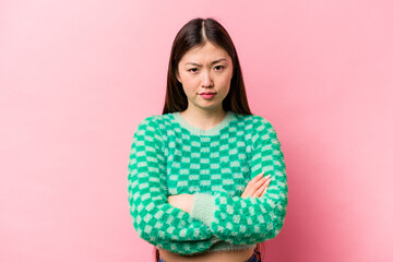Young Chinese woman isolated on pink background frowning face in displeasure, keeps arms folded.