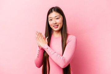 Young Chinese woman isolated on pink background feeling energetic and comfortable, rubbing hands confident.