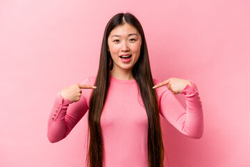 Young Chinese woman isolated on pink background surprised pointing with finger, smiling broadly.