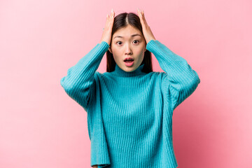 Young Chinese woman isolated on pink background being shocked, she has remembered important meeting.