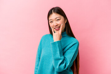 Young Chinese woman isolated on pink background showing rock gesture with fingers