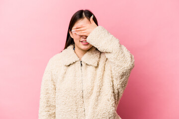 Obraz premium Young Chinese woman isolated on pink background covers eyes with hands, smiles broadly waiting for a surprise.