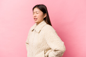 Fototapeta premium Young Chinese woman isolated on pink background suffering a back pain.