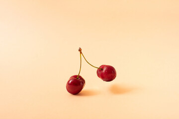 Minimal composition made with fresh red cherry on a pastel coral background. Creative summer fruit concept. Minimal aesthetic.
