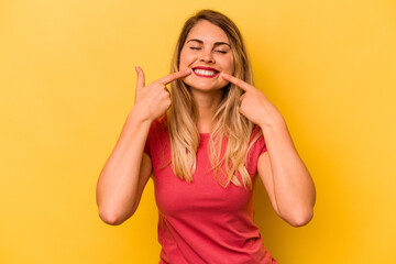 Young caucasian woman isolated on yellow background smiles, pointing fingers at mouth.