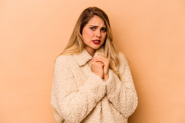 Young caucasian woman isolated on beige background scared and afraid.