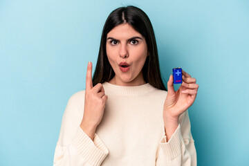 Young caucasian woman holding a batterie isolated on blue background having some great idea, concept of creativity.