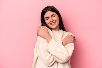 Young caucasian woman isolated on pink background hugs, smiling carefree and happy.