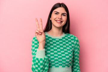 Young caucasian woman isolated on pink background showing number two with fingers.
