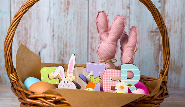 Closeup of easter basket with colorful eggs,toy bannies anf easter wooden sign.April holidays