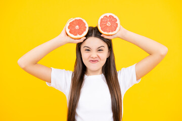 Funny face. Happy teenager girl hold grapefruit orangeisolated on yellow background, kids fruits vitamin.