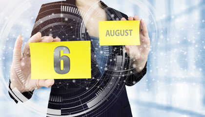 August 6th. Day 6 of month, Calendar date. Business woman hand hold yellow sheet with calendar date on blurred office background.  Summer month, day of the year concept.