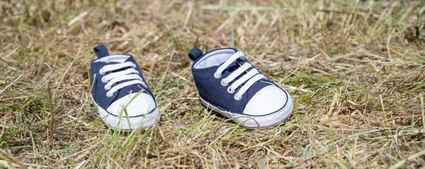petites chaussures pour enfant dans un champ - obrazy, fototapety, plakaty