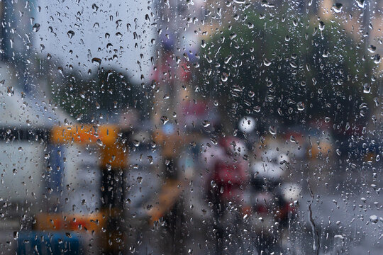 Image shot through raindrops falling on wet glass, abstract blurs of traffic - monsoon stock image of Kolkata (formerly Calcutta) city ,