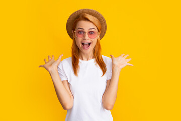 Excited amazed woman in stylish sunglasses and straw hat isolated on yellow studio background....