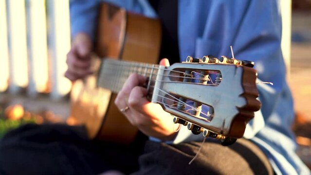 Close up of guitar peg while teenage girl is playing it in the park.