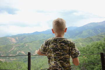 Young thoughtful teenage boy is standing on a balcony and thinking about life.