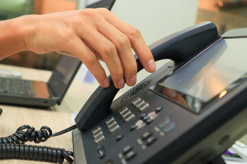 Close-up IP phone on the work desk, The human hand lifted the telephone placed on the table, Hang...