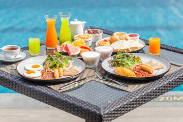 Delicious breakfast in luxury hotel. Vacation in resort by the water in tropics. Summer travel holiday. Outdoor restaurant served meal on table for two with exotic fruits, eggs and pastry