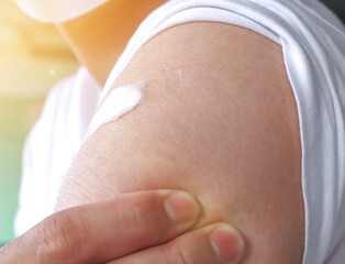 Man with an adhesive bandage on the shoulder from getting vaccine shot in the arm. 