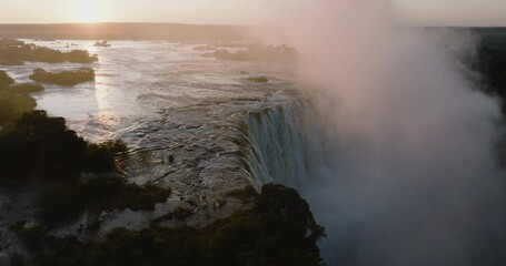 Aerial close-up sunrise view of the mist and water flowing over the edge of the Victoria Falls, Unesco world heritage site
