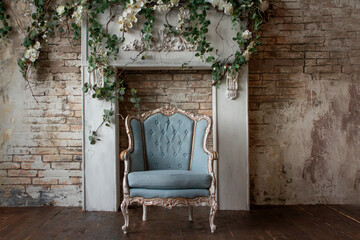 Old antique armchair furniture against a light gray grunge wall, stucco, and vines with flowers...