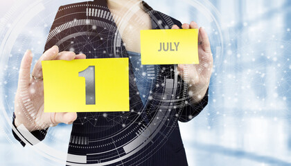 July 1st . Day 1 of month, Calendar date. Business woman hand hold yellow sheet with calendar date...