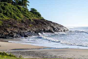 Fototapeta na wymiar Beautiful beach with rough seas and strong waves crashing against the rocks