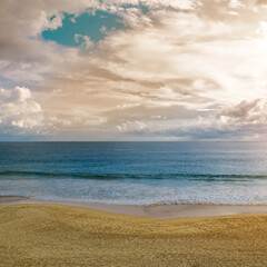 Sandy beach, blue ocean water and bright sun.