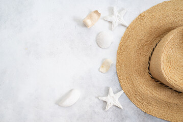 Fototapeta na wymiar Straw hat with and seashells on light grey background with empty place fpr text. Sea consept.