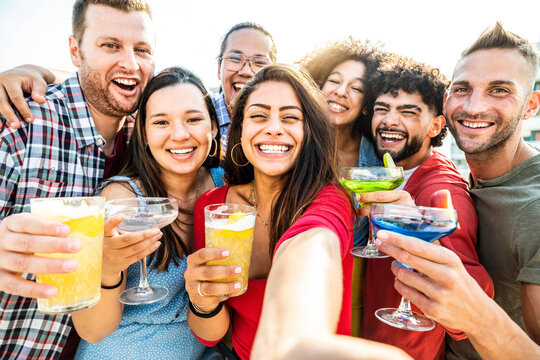 Multicultural group of friends making cocktail party outside - Happy young people taking selfie at bar restaurant - Friendship concept with guys and girls enjoying day out together