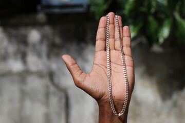 Pure silver chain that can be worn as a necklace held in hand against a nature background