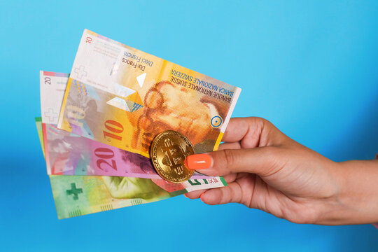Hand holding swedish krona banknotes and bitcoin over blue background