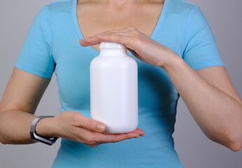 White blank plastic bottle jar in woman hands closeup. Mockup, copyspace.