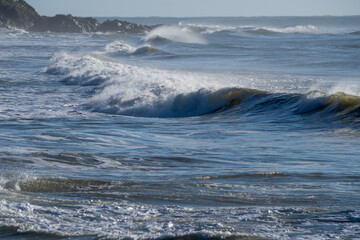 Beautiful beach with rough seas and strong waves crashing against the rocks