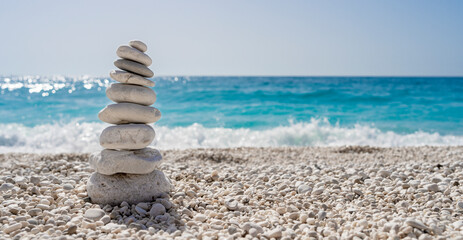 Fototapeta na wymiar Stacked stones on a beautiful white pebble beach in the Mediterranean