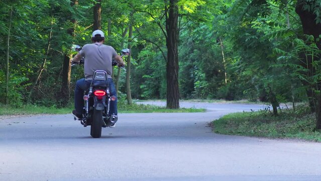 Man Riding A Motorcycle Through The Woods. He moves away from the camera.