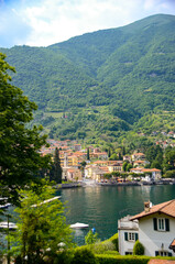 Fototapeta na wymiar Scenic view in Como lake, Italy with waterfront town and mountain in the back. Summer holidays and travel destination in Europe for relaxation and romance