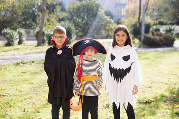 Happy smiling kids wearing carnival costumes of vampire, pirate and ghost celebrating Halloween,...