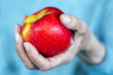 close-up of old womans hand holding a red apple