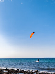 Person kiteboarding on sea waves on blue skyline background. Kitesurfing on Cyprus