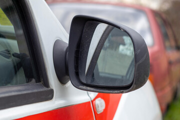 Side right black plastic rearview mirror on a white car. Exterior side view mirror on the passenger side, electrically adjustable and heated.