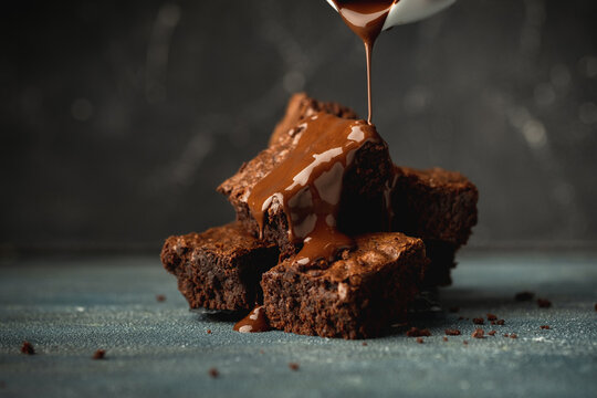 Pieces of chocolate biscuit brownie covered with melted dark chocolate on the black background