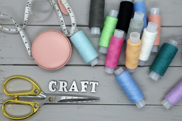 Set of sewing accessories on a wooden background. Fabric, threads, centimeter and scissors.
