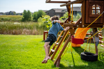 Caucasian male boy jumping from a swing set in midair falling