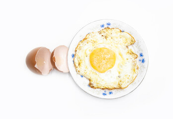 fried egg in a plate with broken egg skin isolated on white background on top view. Food cooking