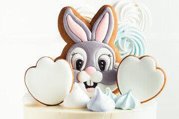 Easter cake with white cream cheese frosting decorated with bunny shaped gingerbread cookies on the white background