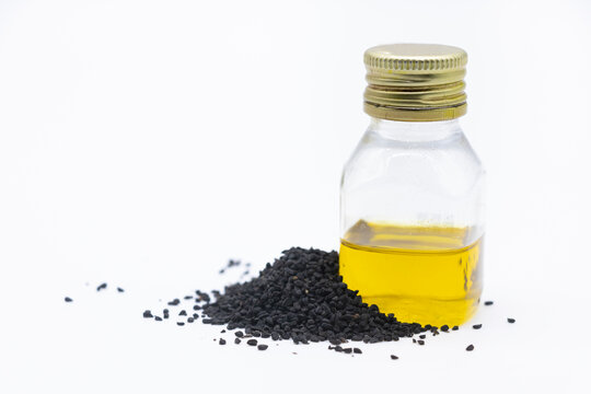 Black cumin with black cumin oil over white background.