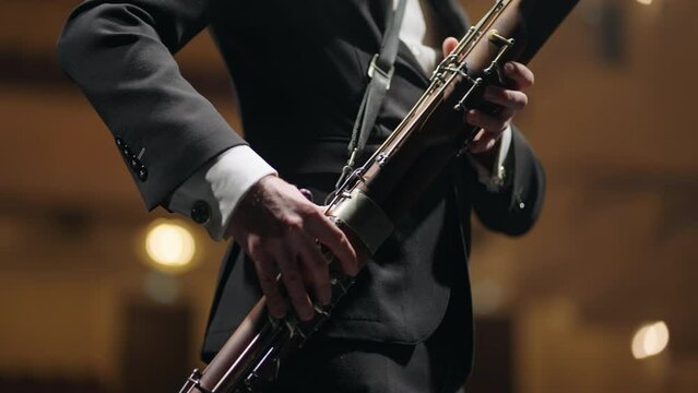 talented bassoonist is playing music during concert in opera house, musician with bassoon on scene
