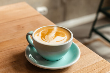 Delicious and stylish cappuccino with beautiful foam in a blue cup on a wooden table. Hot coffee with almond milk in a coffee shop. Vegan Vegetable Milk for Breakfast